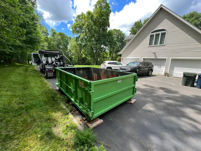 Green dumpster delivered to residential driveway