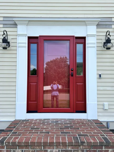 Deep red entry door with white surround on a brick step