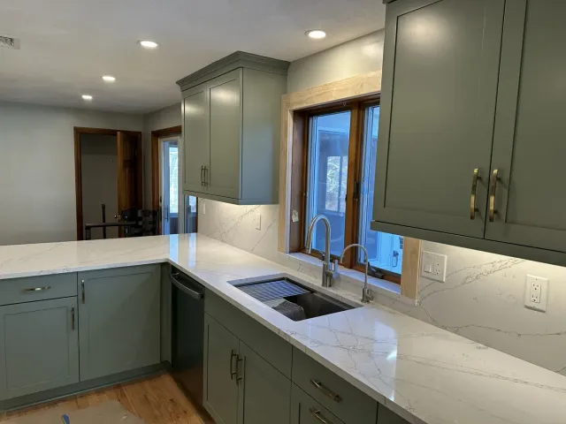 Renovated kitchen with recessed ceiling lights, under-cabinet lighting and quartz counters