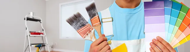 Painter holding brushes on one hand and color samples on the other