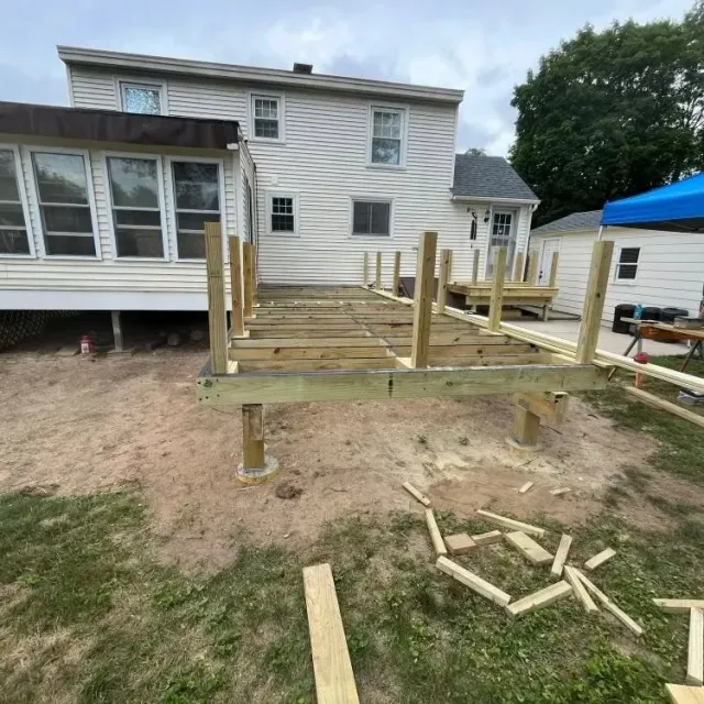 Partially built wooden backyard deck attached to a house, with posts and framing visible.