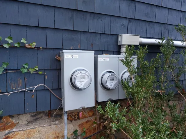 Exterior meter sockets and service mast on a shingled home