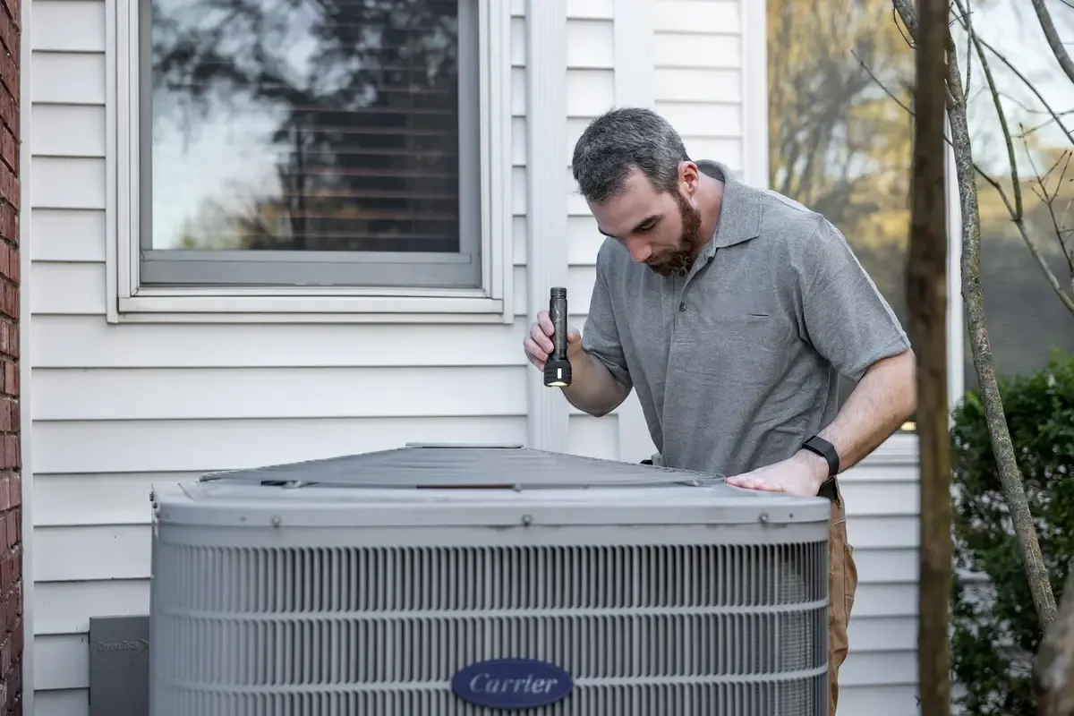 Technician inspecting the electrical connections of a residential HVAC condenser unit