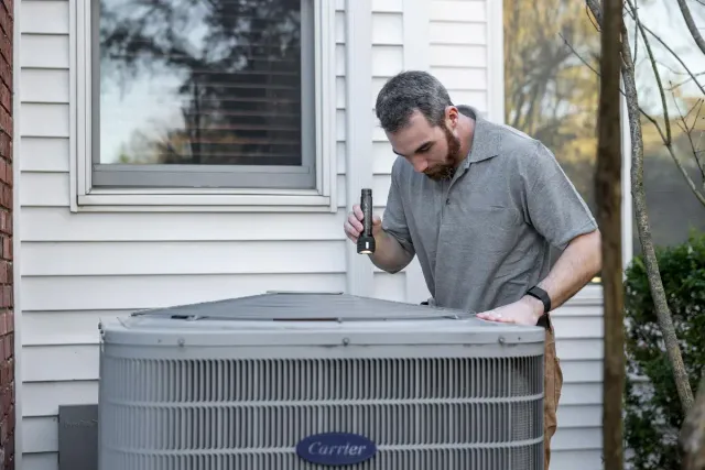Technician inspecting the electrical connections of a residential HVAC condenser unit