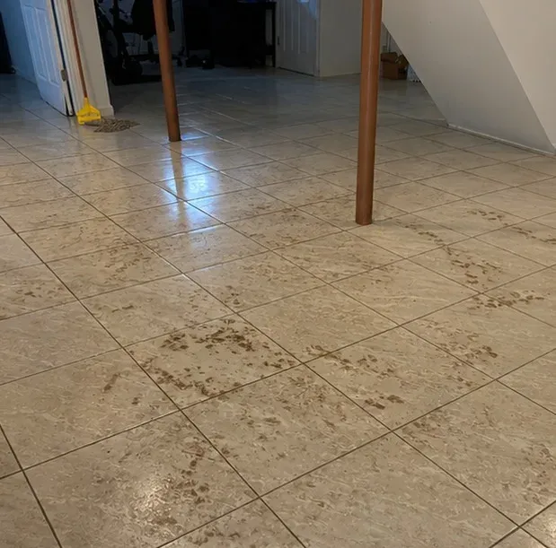 Basement tile floor streaked with sewage debris after a backup, before Restorehaus cleaned it