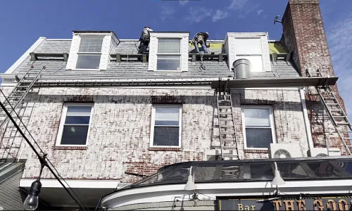 Team of technical workers work on the roof of a house