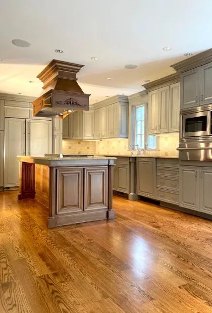 A kitchen with wooden floors and cabinets, and a large island.