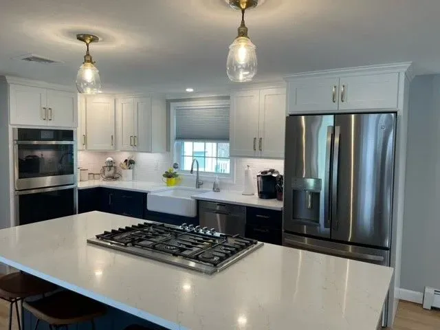 Modern kitchen with white and navy cabinets, stainless steel appliances, and a large island.