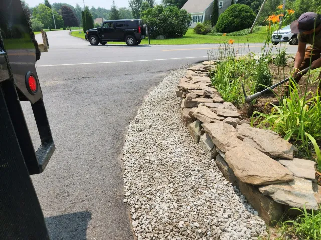 a stone wall next to a road