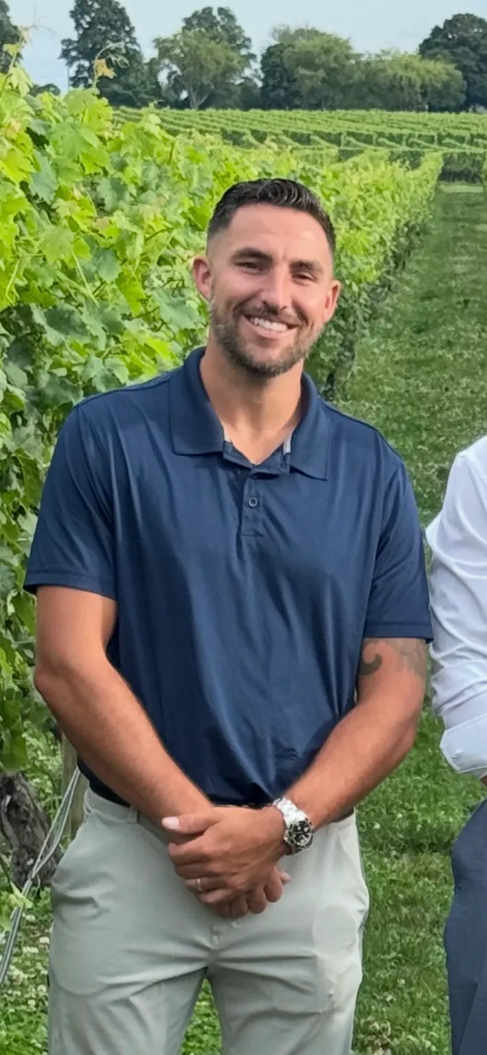 Ryan Morrison smiling outdoors in a navy polo shirt