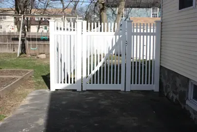 White vinyl gate and picket fence at a side yard