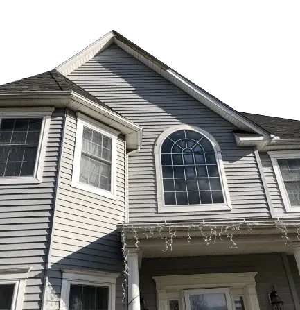 A low-angle view of the front exterior of a gray, two-story vinyl-sided home with a prominent arched window.