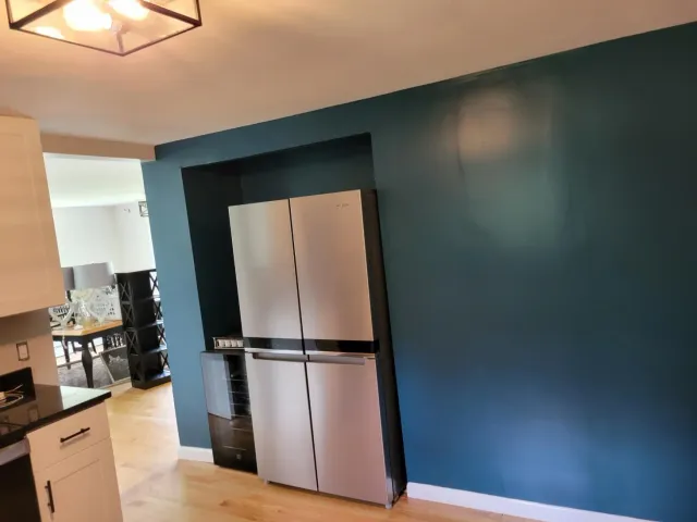 A kitchen with blue walls and a stainless steel refrigerator.