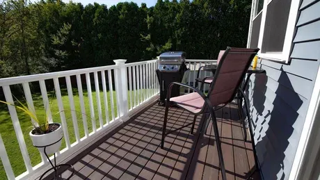 A wooden deck with a black railing and stairs leading up to it.