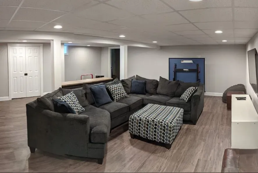A living room with a large sectional couch and ottoman.