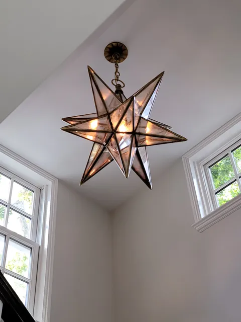 Decorative star pendant fixture installed in a tall stairwell