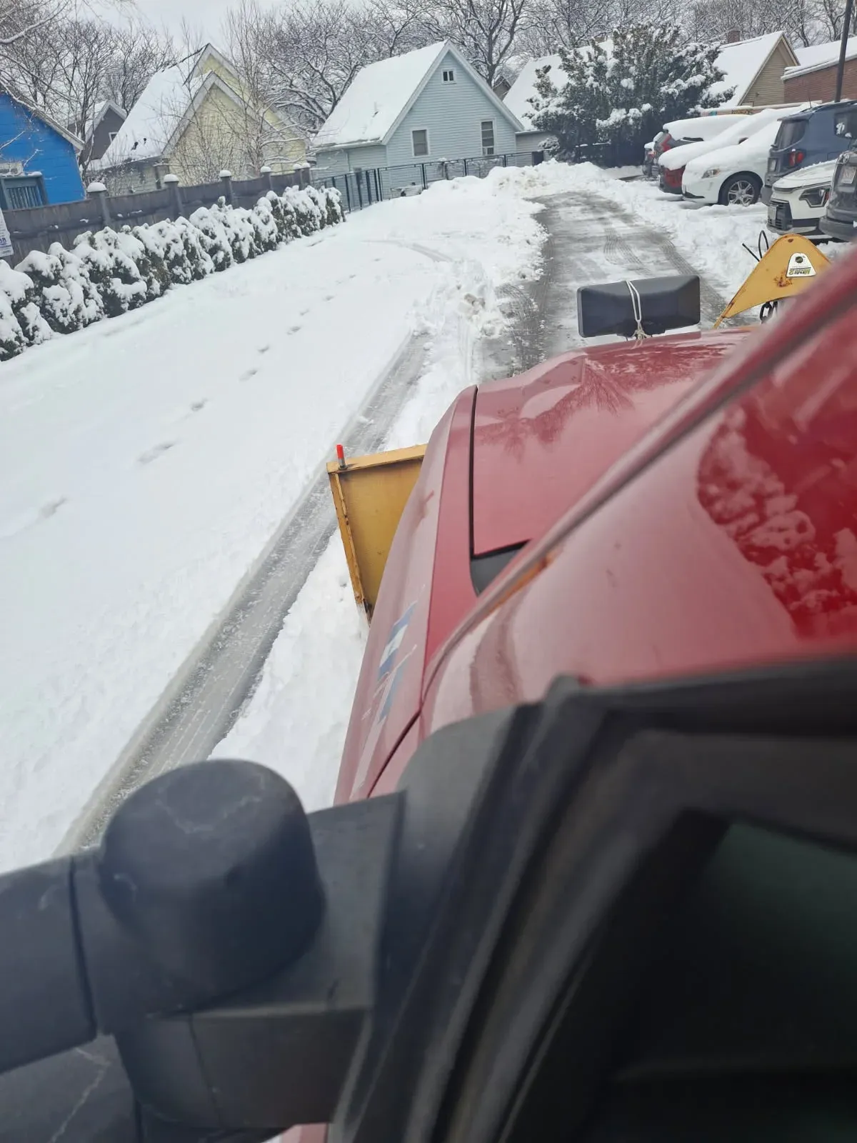 Red truck plowing snow from residential driveway for clear winter access