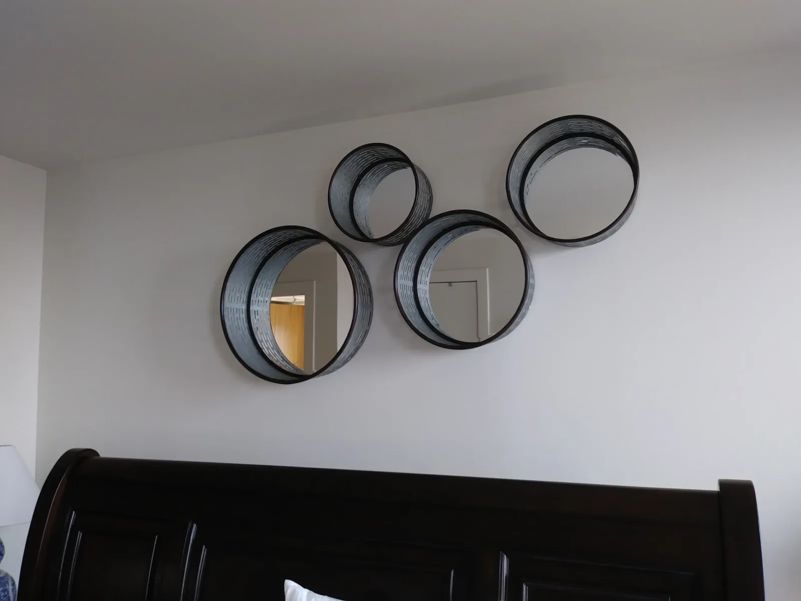 Cluster of round mirrors hung above a sleigh bed