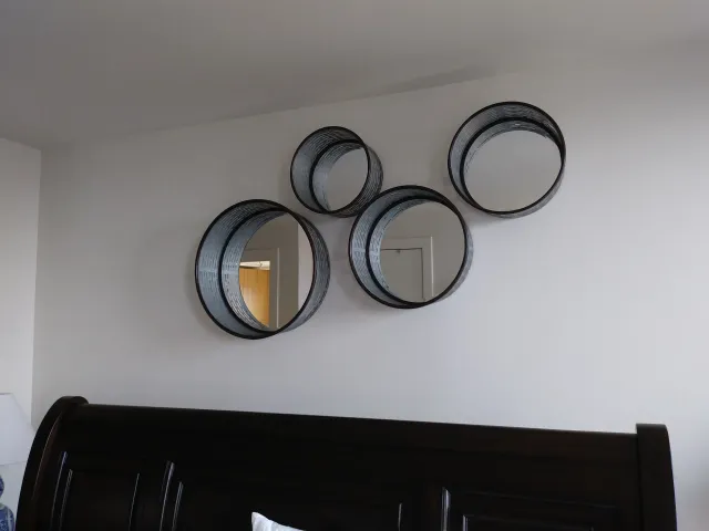 Cluster of round mirrors hung above a sleigh bed