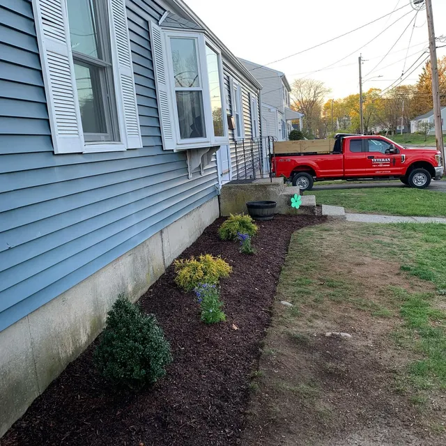 New foundation planting bed dug and mulched at a blue house