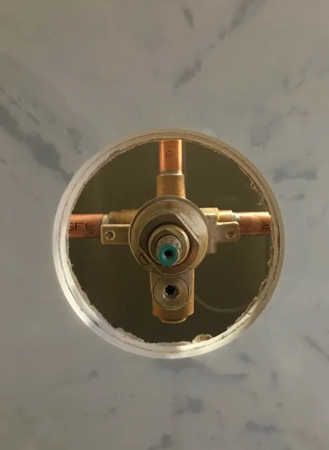 Close-up of a plumbing valve installed in a wall with visible copper pipes.