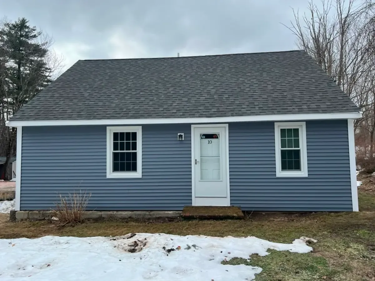 Finished front elevation of a Cape in Atkinson, NH with blue-grey vinyl siding and white trim