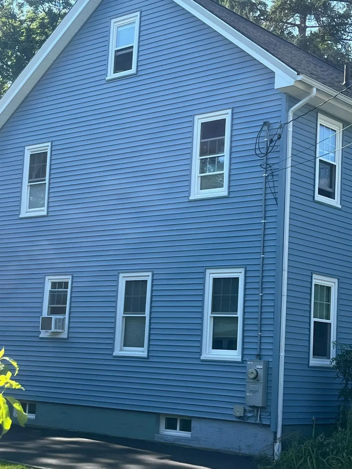 Blue-sided two-story house with white window frames, and a ladder attached to the side.