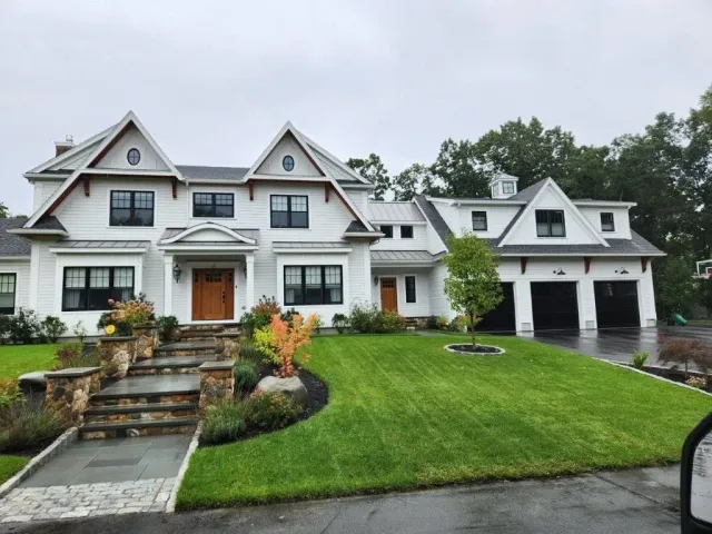A large white house with a lush green lawn in front of it.