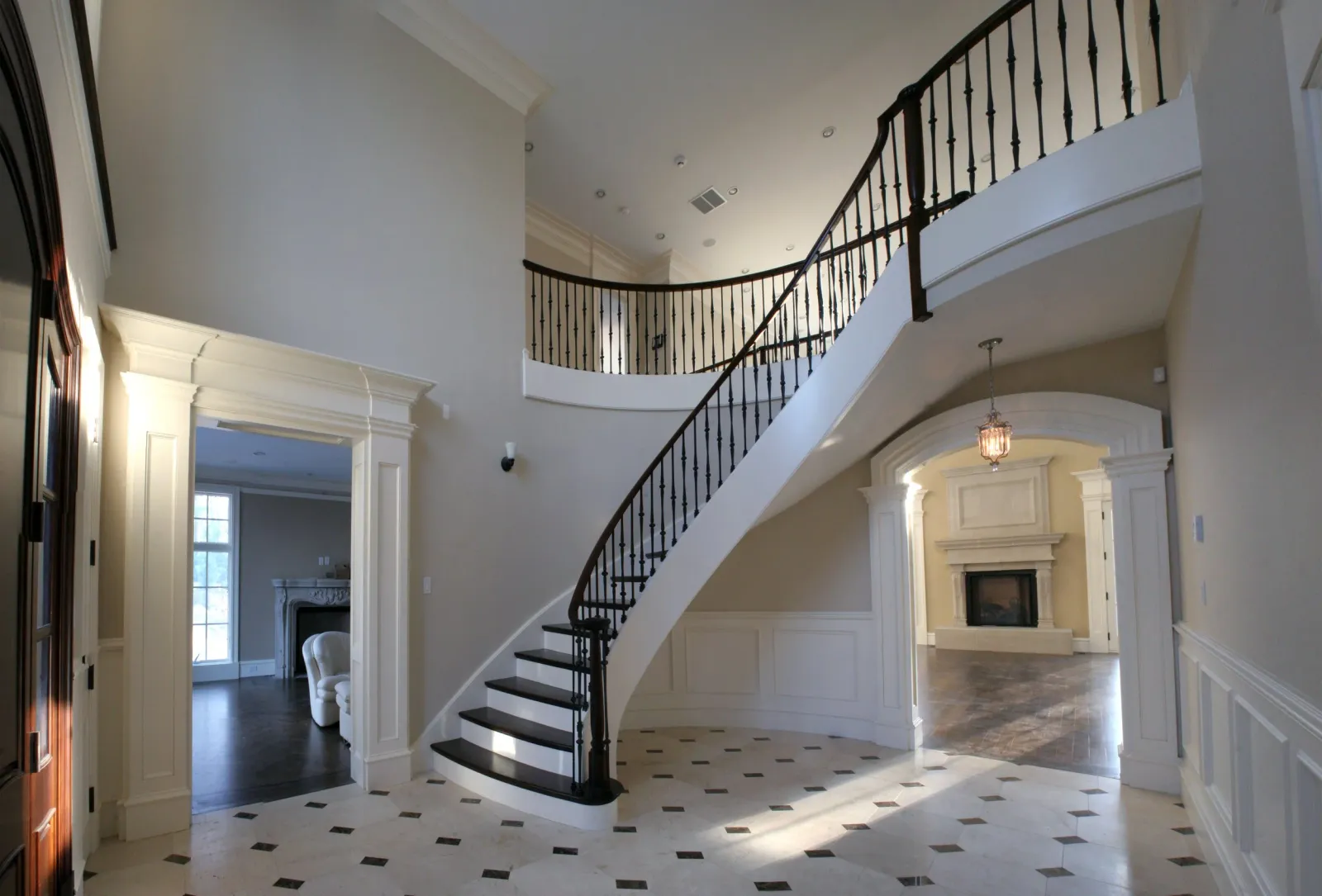 Interior view of a luxurious home with a curved staircase, fireplace, and elegant architectural details.