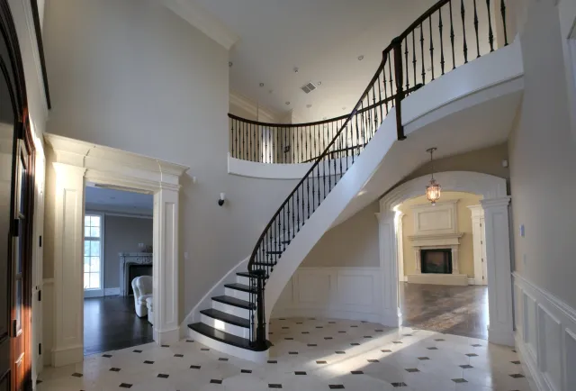 Interior view of a luxurious home with a curved staircase, fireplace, and elegant architectural details.