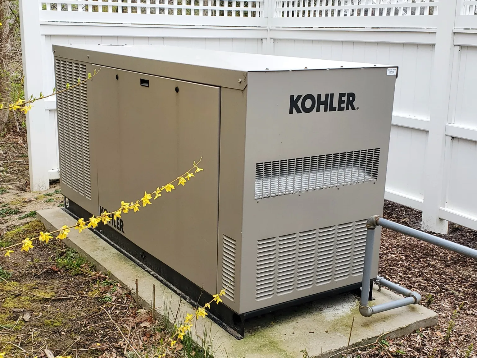 Kohler generator installed beside white fence