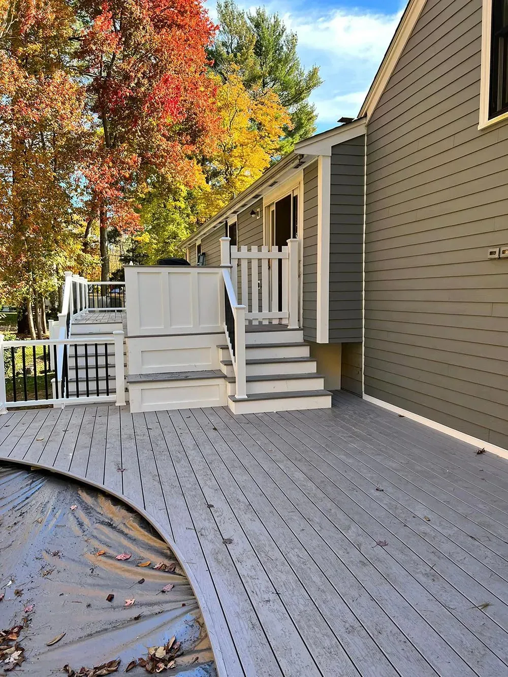 A wooden deck with stairs and a house in the background