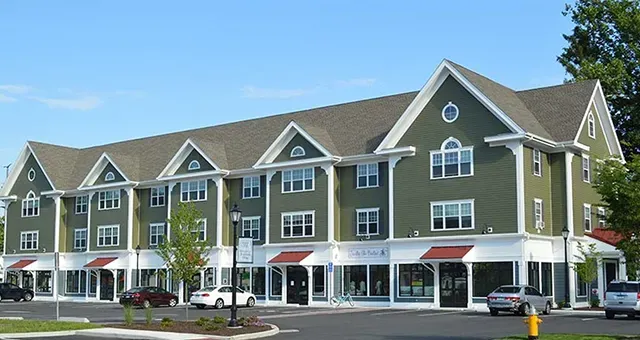A large green building with a lot of windows and cars parked in front of it