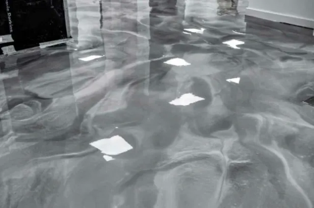 A wet floor with scattered pieces of paper or debris, reflections on the surface, and some objects in the background.
