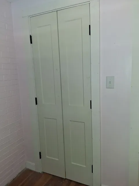 New double closet doors hung and cased over hardwood flooring