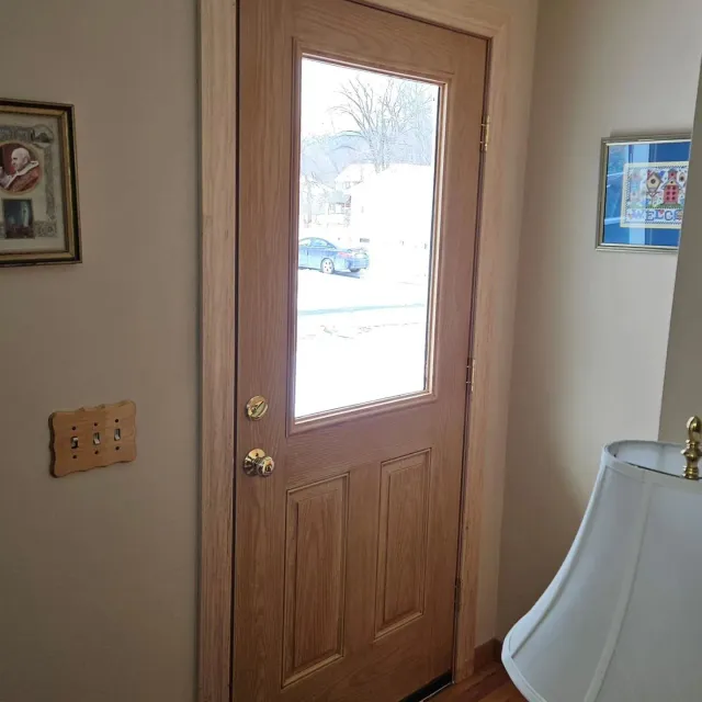 Wooden front door with glass pane, viewed from inside a home.