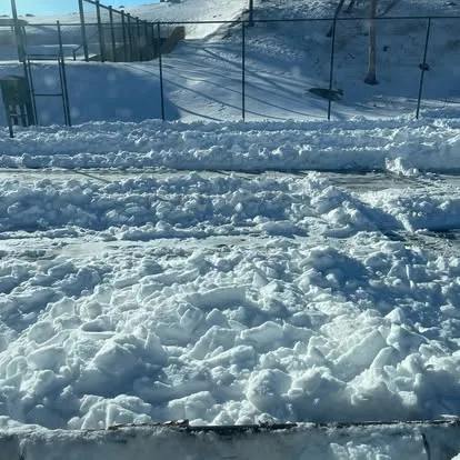 Snow removal clearing walkway near sports court