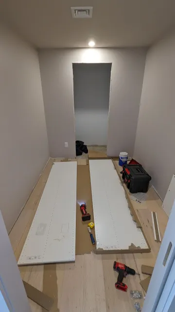 A room with a drill and a few pieces of wood on the floor.