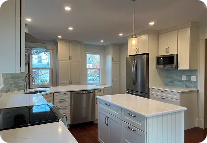 Bright white kitchen with center island, stainless fridge, microwave, dishwasher.