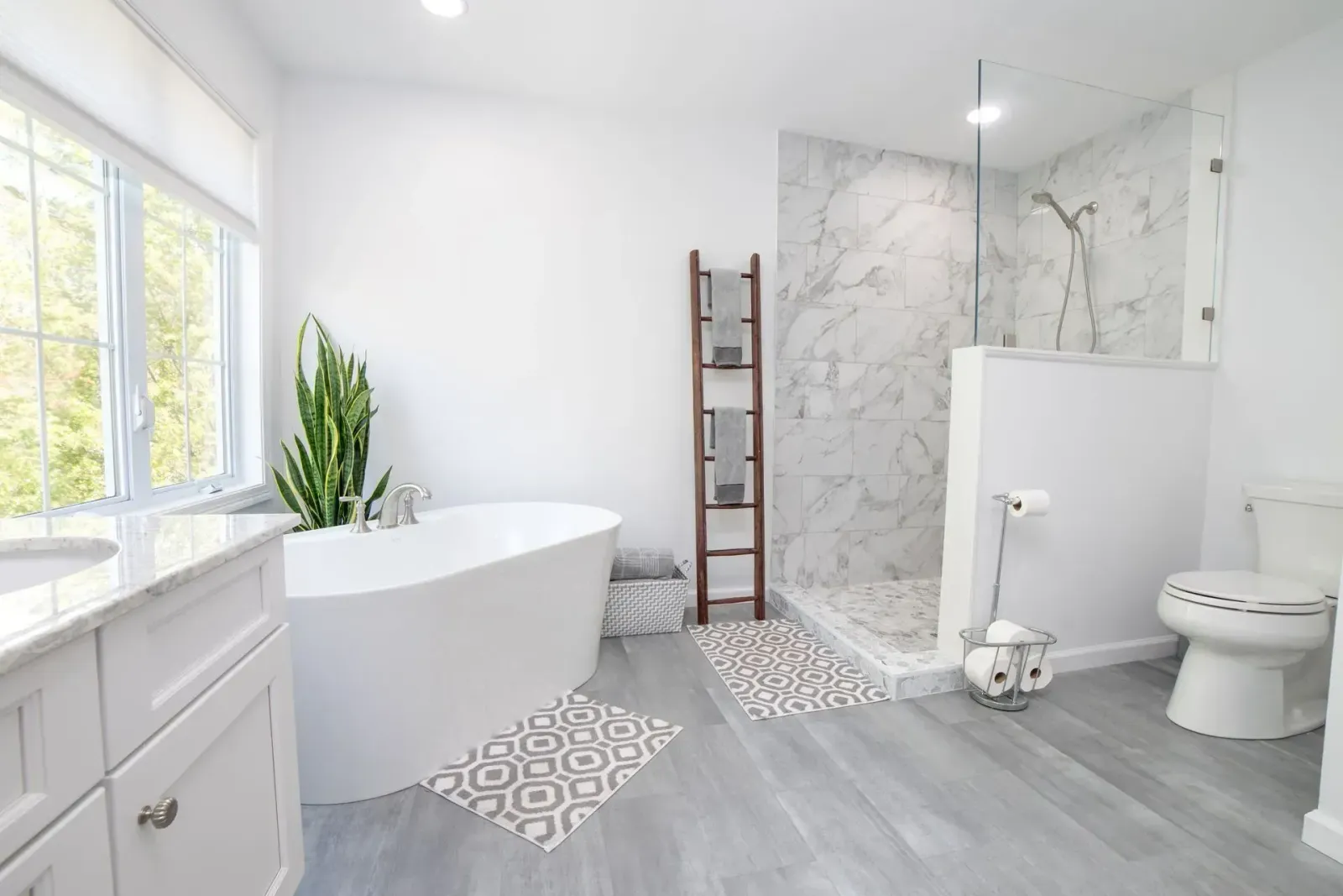 Bright modern bathroom with white tub, walk-in shower, toilet, and gray patterned tile accents