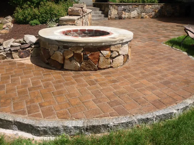 A fire pit is sitting on top of a brick patio