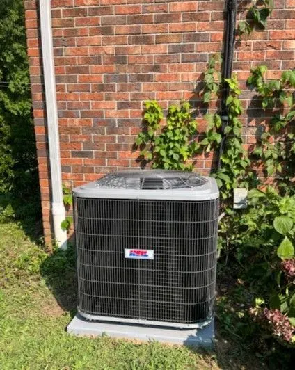 An air conditioner is sitting on the side of a brick building.