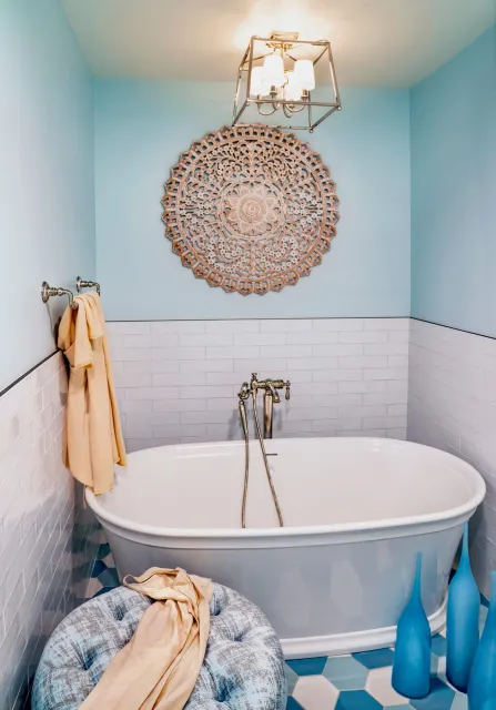A bathtub with gold faucets and a towel hanging on the wall.