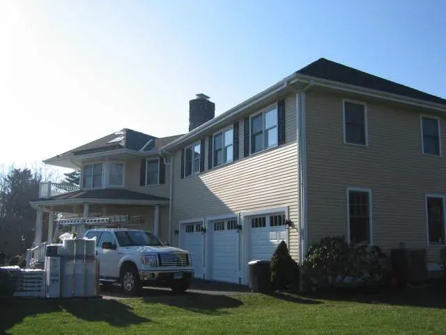A white truck is parked in front of a large house