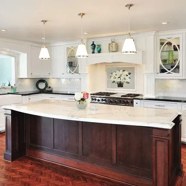 Elegant kitchen with white cabinets, dark wood island, and pendant lights.