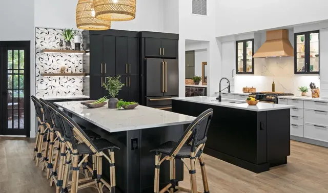 Modern kitchen with black island, white marble countertops, custom cabinetry, and brass range hood
