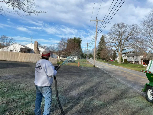 Parker crew member applying hydroseed across a prepared roadside lot