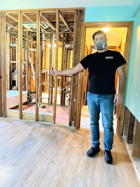 BRG technician wearing respiratory protection beside opened interior wall framing