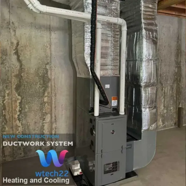HVAC system with ductwork in a basement setting. Gray furnace, silver ductwork, and exposed concrete wall.