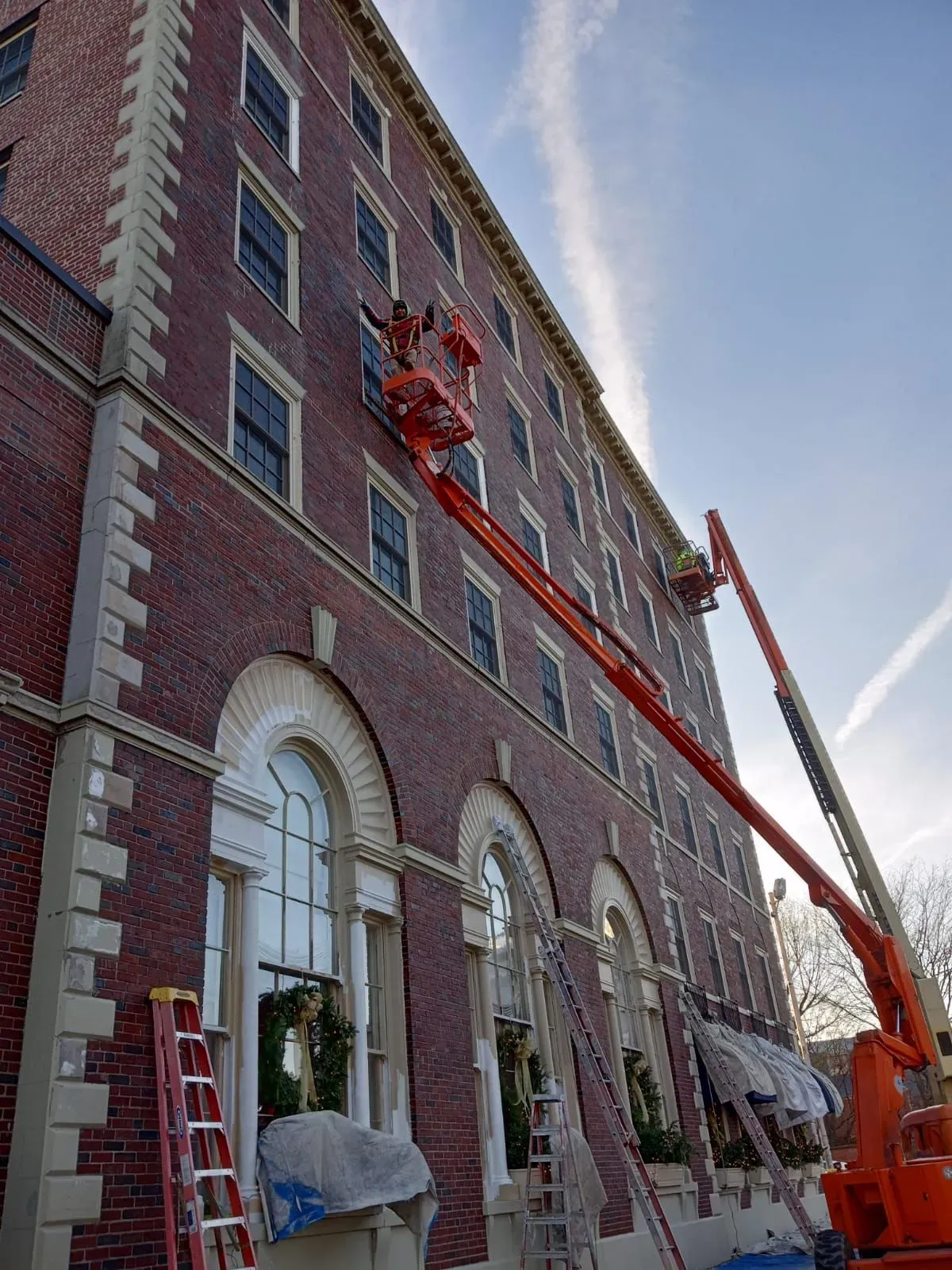 A large brick building is being painted with a crane.